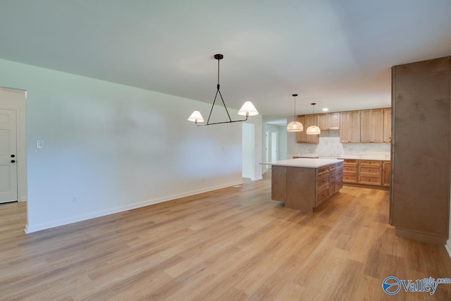 kitchen with decorative backsplash, hanging light fixtures, a center island, a notable chandelier, and light wood-type flooring