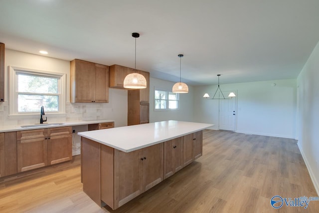 kitchen featuring sink, hanging light fixtures, light wood-type flooring, a kitchen island, and decorative backsplash