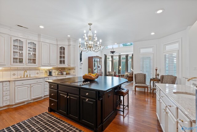 kitchen with a sink, black electric stovetop, white cabinetry, a chandelier, and recessed lighting