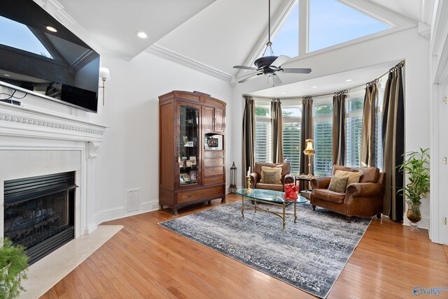 living room with high vaulted ceiling, plenty of natural light, light wood-type flooring, a high end fireplace, and crown molding