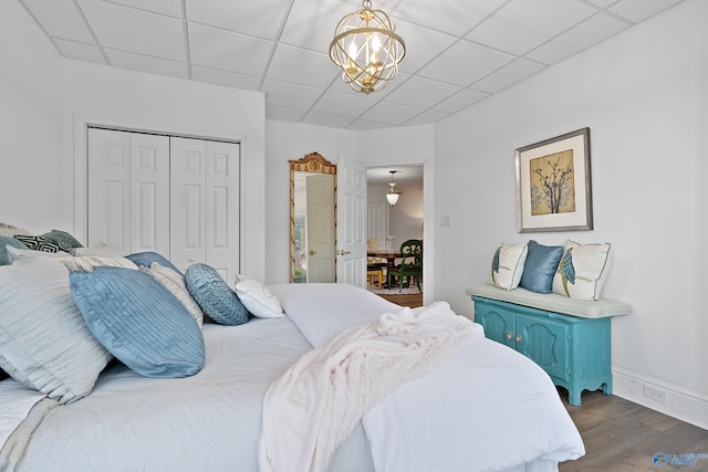 bedroom featuring a closet, dark wood finished floors, a drop ceiling, and a chandelier