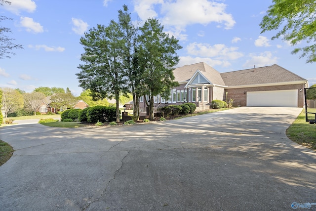view of front of home with concrete driveway, brick siding, a garage, and a shingled roof