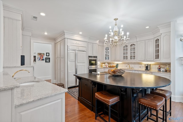kitchen featuring a sink, decorative backsplash, light wood-type flooring, a kitchen bar, and recessed lighting