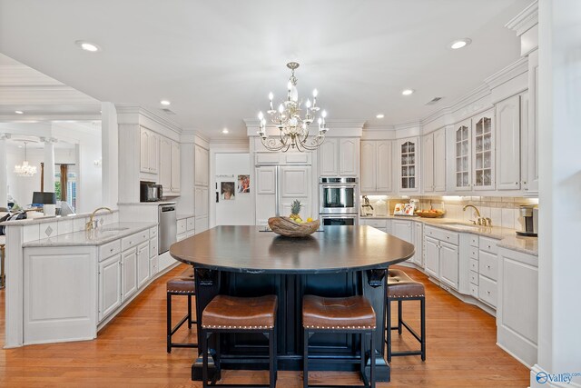 kitchen featuring a chandelier, a sink, stainless steel appliances, glass insert cabinets, and recessed lighting