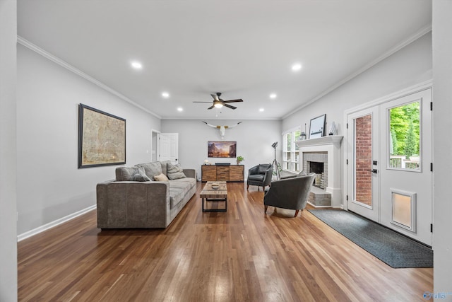 living room featuring crown molding, recessed lighting, wood finished floors, and a fireplace