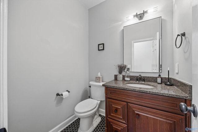 half bath featuring baseboards, tile patterned floors, toilet, and vanity