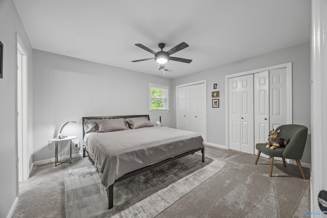 bedroom with two closets, baseboards, ceiling fan, and carpet