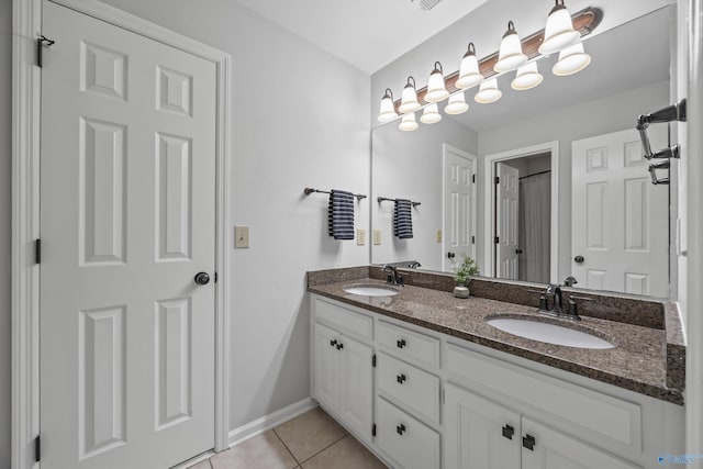 bathroom featuring tile patterned flooring, a sink, baseboards, and double vanity