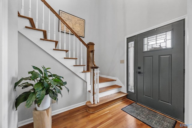 foyer with stairway, baseboards, wood finished floors, and a towering ceiling