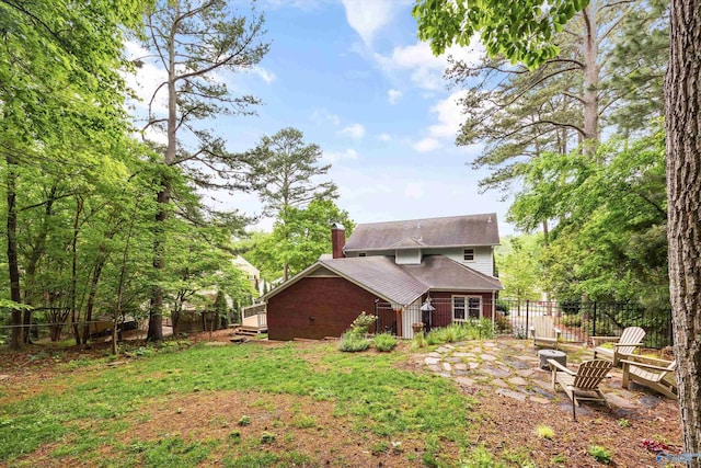 back of house featuring a fenced backyard, a chimney, and brick siding
