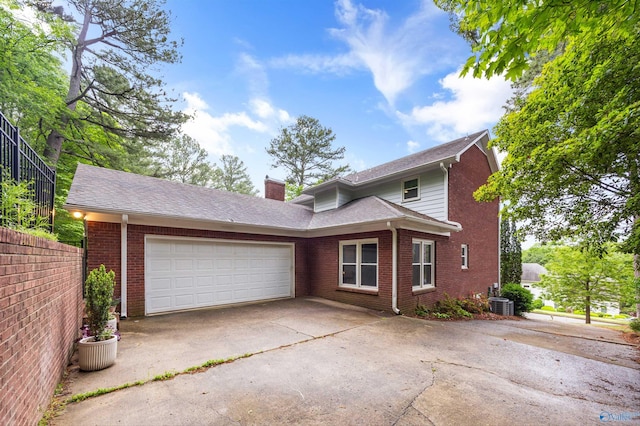 view of front of home with a chimney, a garage, brick siding, cooling unit, and concrete driveway