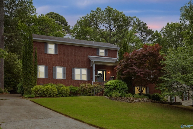 view of front of home with brick siding, driveway, and a front lawn
