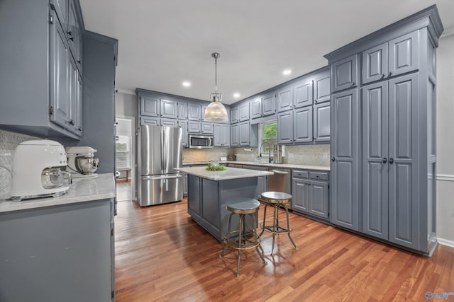 kitchen featuring decorative backsplash, light wood-style floors, a center island, gray cabinetry, and stainless steel appliances