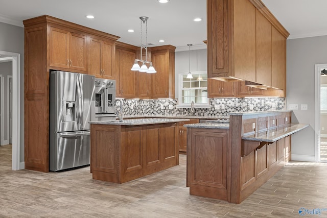 kitchen featuring stainless steel appliances, brown cabinetry, and light stone counters