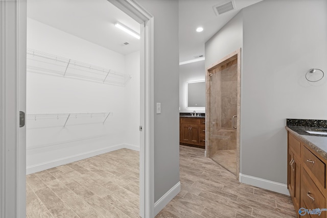 bathroom featuring a sink, visible vents, two vanities, and a stall shower
