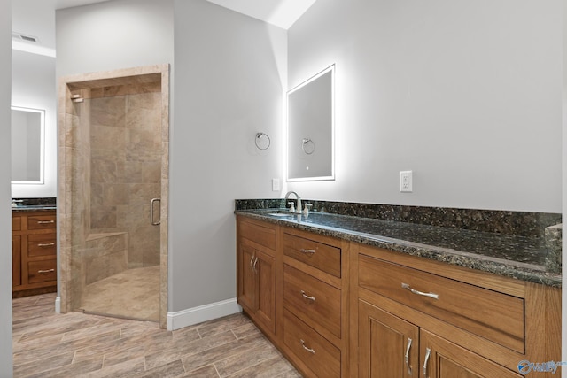 bathroom featuring vanity, visible vents, wood tiled floor, a stall shower, and baseboards