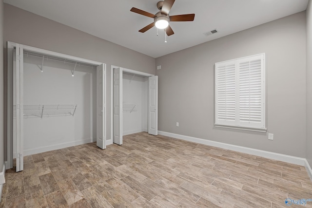 unfurnished bedroom featuring light wood finished floors, visible vents, baseboards, and two closets