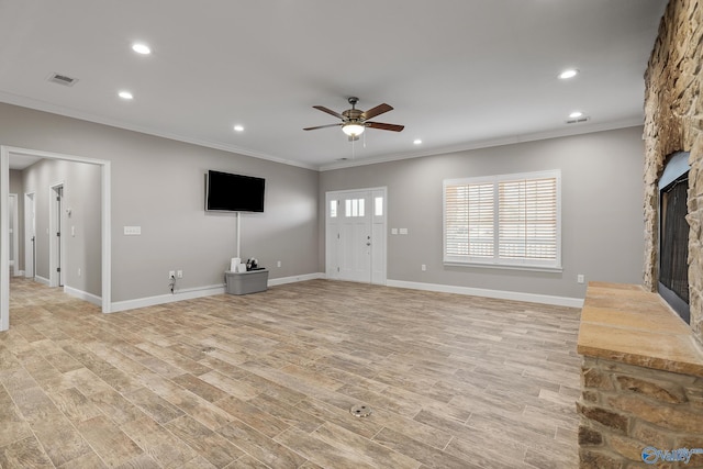unfurnished living room featuring crown molding, ceiling fan, a stone fireplace, visible vents, and light wood finished floors