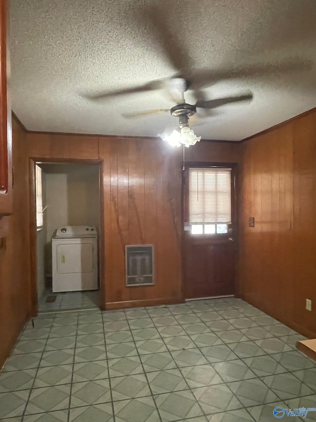 unfurnished room featuring a textured ceiling, wooden walls, heating unit, and ceiling fan