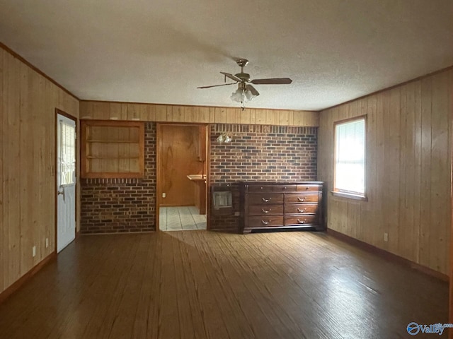 spare room featuring wood-type flooring, wood walls, a ceiling fan, and ornamental molding