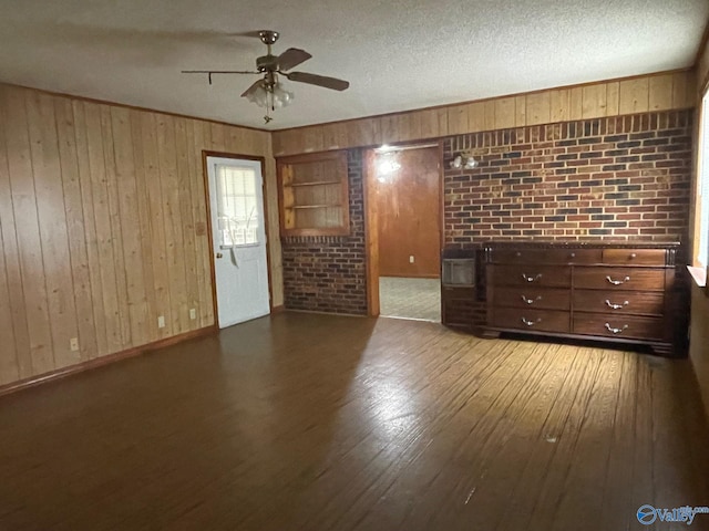 empty room featuring wood walls, a textured ceiling, and wood finished floors