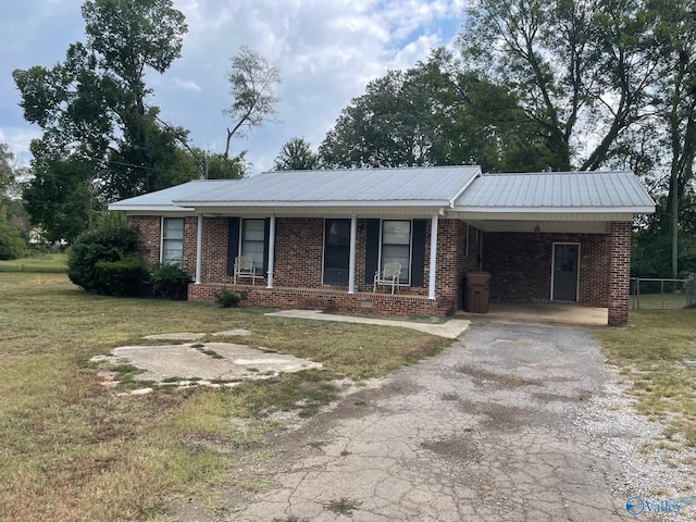 ranch-style house with aphalt driveway, brick siding, metal roof, and a front yard