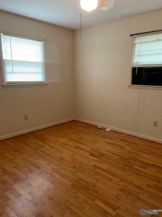 unfurnished room with plenty of natural light, wood finished floors, and baseboards