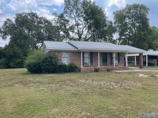 ranch-style house featuring an attached carport, brick siding, metal roof, and a front yard