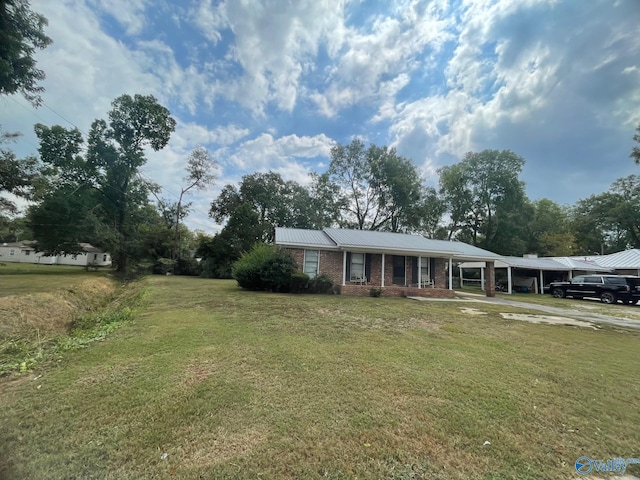 ranch-style home featuring brick siding, metal roof, a front yard, and a carport