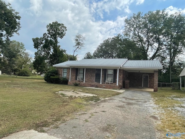 ranch-style home featuring brick siding, a front lawn, aphalt driveway, metal roof, and a carport