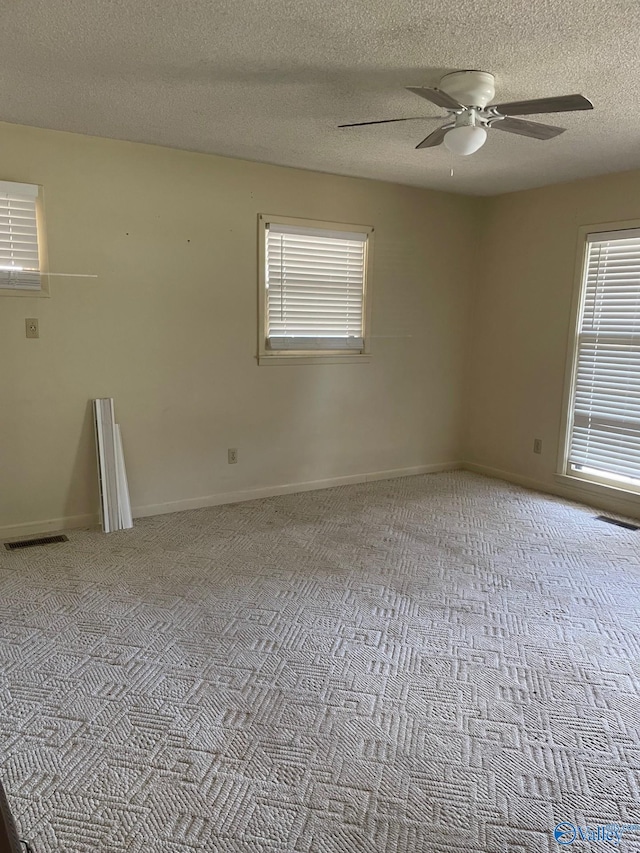 unfurnished room featuring carpet flooring, baseboards, visible vents, and ceiling fan