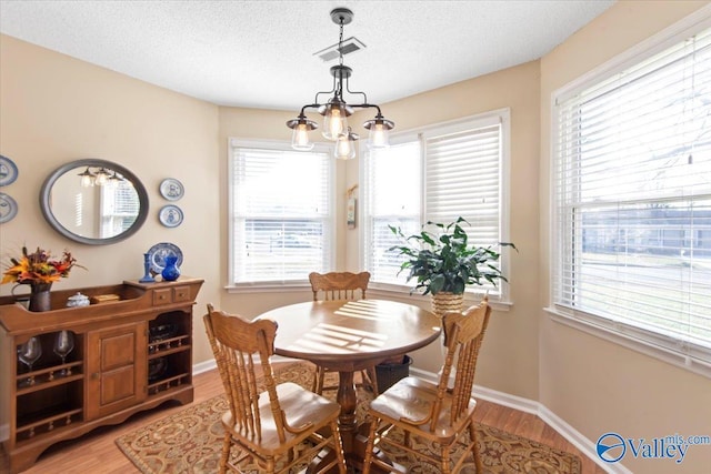 dining space featuring hardwood / wood-style floors, a textured ceiling, and an inviting chandelier