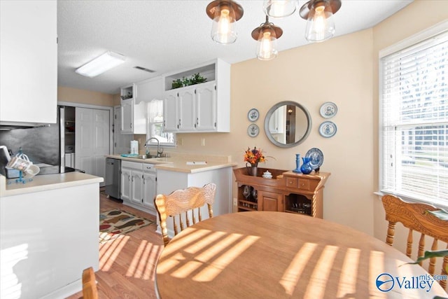 kitchen featuring white cabinetry, dishwasher, light hardwood / wood-style floors, and sink