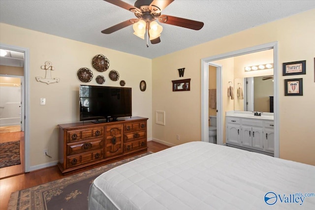 bedroom featuring sink, ceiling fan, a textured ceiling, connected bathroom, and dark hardwood / wood-style flooring