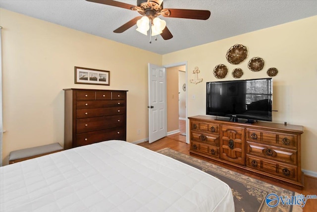 bedroom with ceiling fan, light hardwood / wood-style flooring, and a textured ceiling