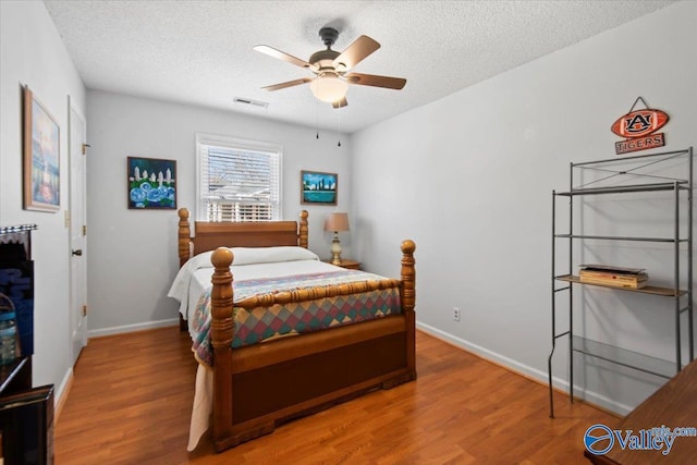 bedroom featuring ceiling fan, wood-type flooring, and a textured ceiling