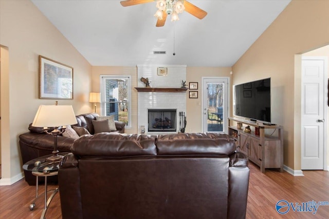 living room with a fireplace, ceiling fan, hardwood / wood-style floors, and lofted ceiling