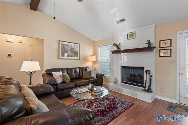 living room with vaulted ceiling with beams, wood-type flooring, and a fireplace