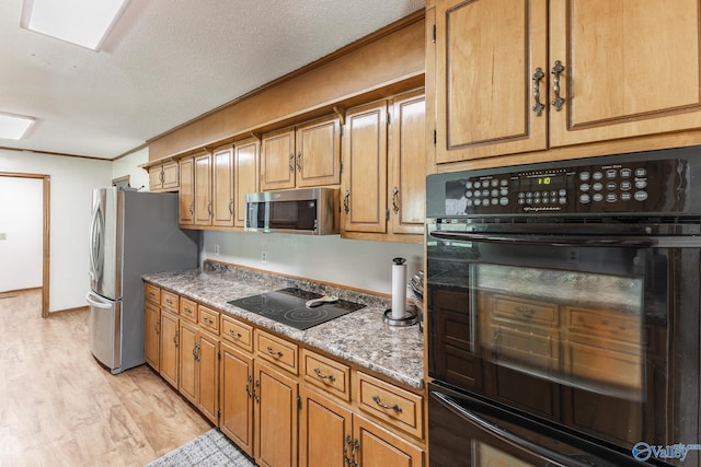 1104 Princeton Dr, Madison, AL 35758 - kitchen featuring black appliances, light wood-style flooring, brown cabinetry, and a textured ceiling