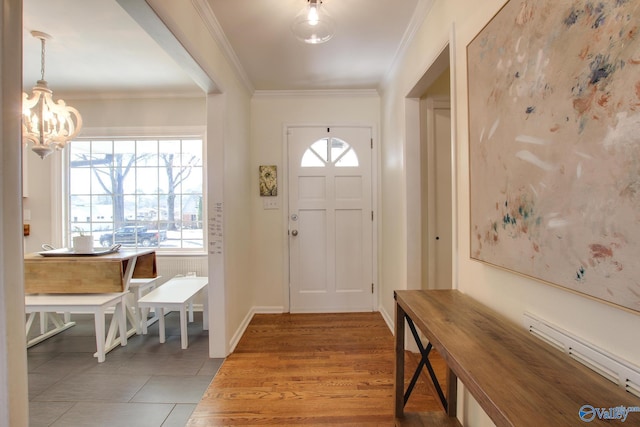 entryway with a baseboard radiator, wood-type flooring, ornamental molding, and a chandelier