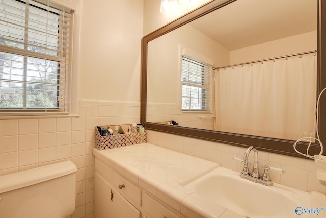 bathroom with toilet, sink, and tile walls