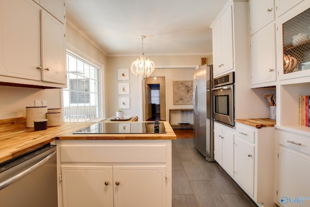 kitchen with hanging light fixtures, white cabinetry, wood counters, and stainless steel appliances