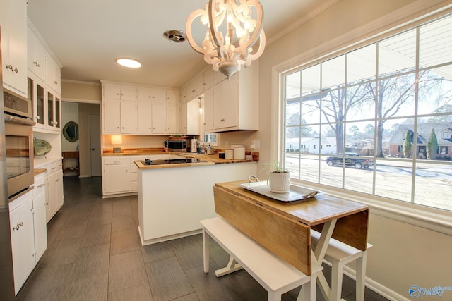 kitchen with white cabinetry, crown molding, and decorative light fixtures