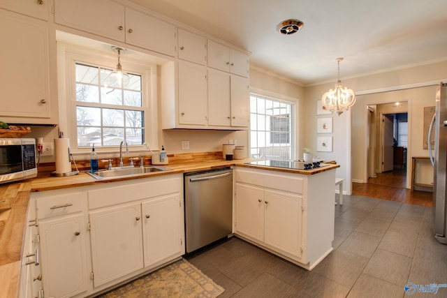 kitchen with sink, white cabinetry, hanging light fixtures, stainless steel appliances, and a healthy amount of sunlight