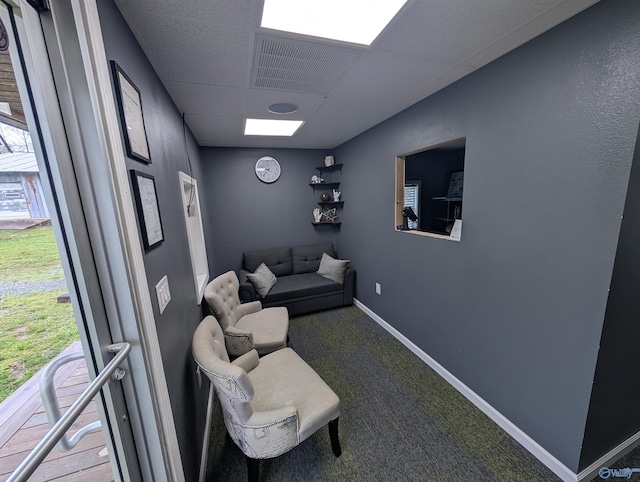 carpeted living area with baseboards, a drop ceiling, and visible vents