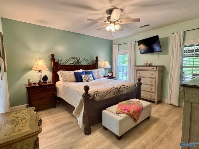 bedroom with light wood finished floors, baseboards, visible vents, and multiple windows