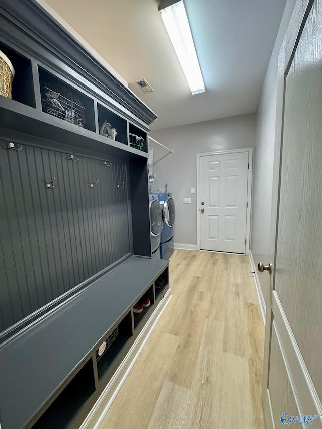 mudroom featuring separate washer and dryer, baseboards, visible vents, and light wood-style flooring