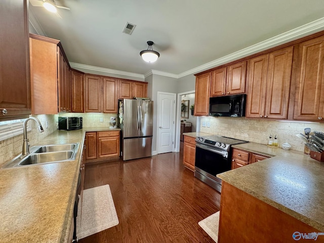 kitchen with a sink, tasteful backsplash, visible vents, appliances with stainless steel finishes, and ornamental molding