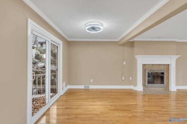 unfurnished living room with ornamental molding, a premium fireplace, light hardwood / wood-style floors, and a textured ceiling