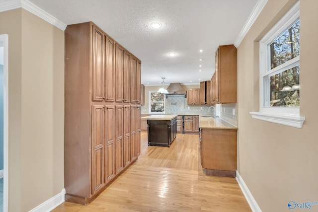 kitchen with light hardwood / wood-style flooring, a kitchen island, crown molding, a textured ceiling, and light stone countertops